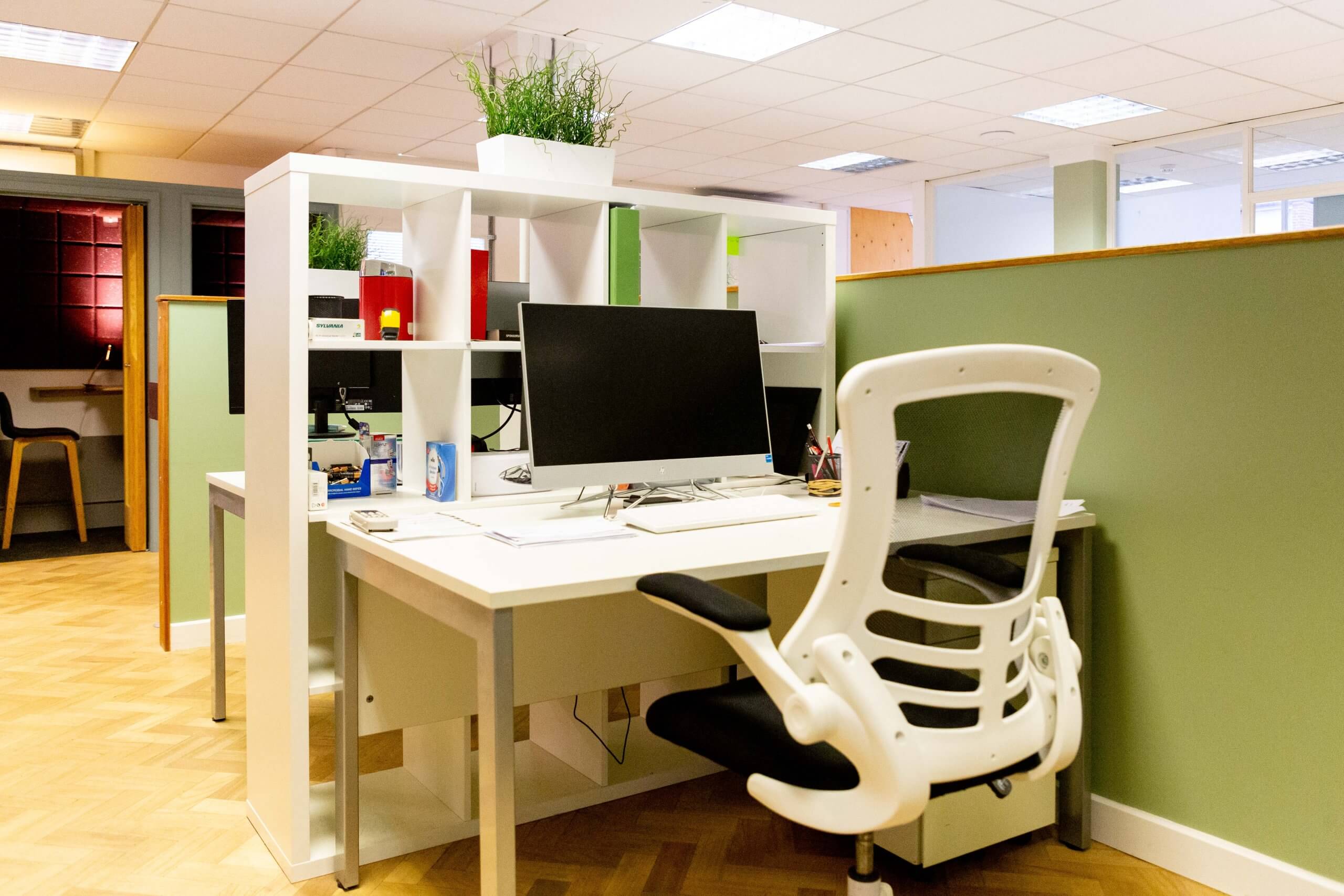 CoWorking Desk with a monitor and keyboard setup on it. Located in a larger CoWorking space.