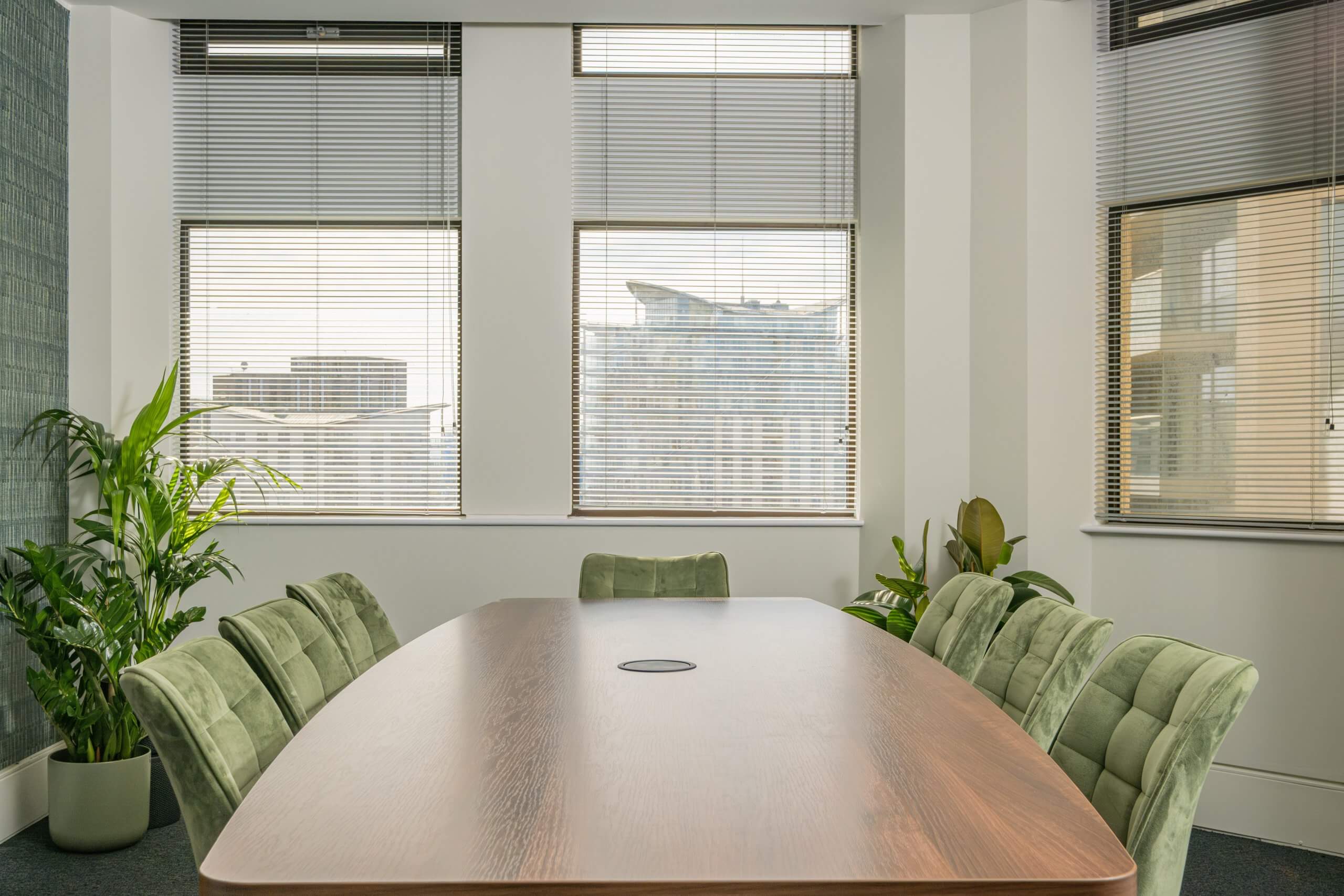 Closeup shot of a meeting room table with seven chairs showing.