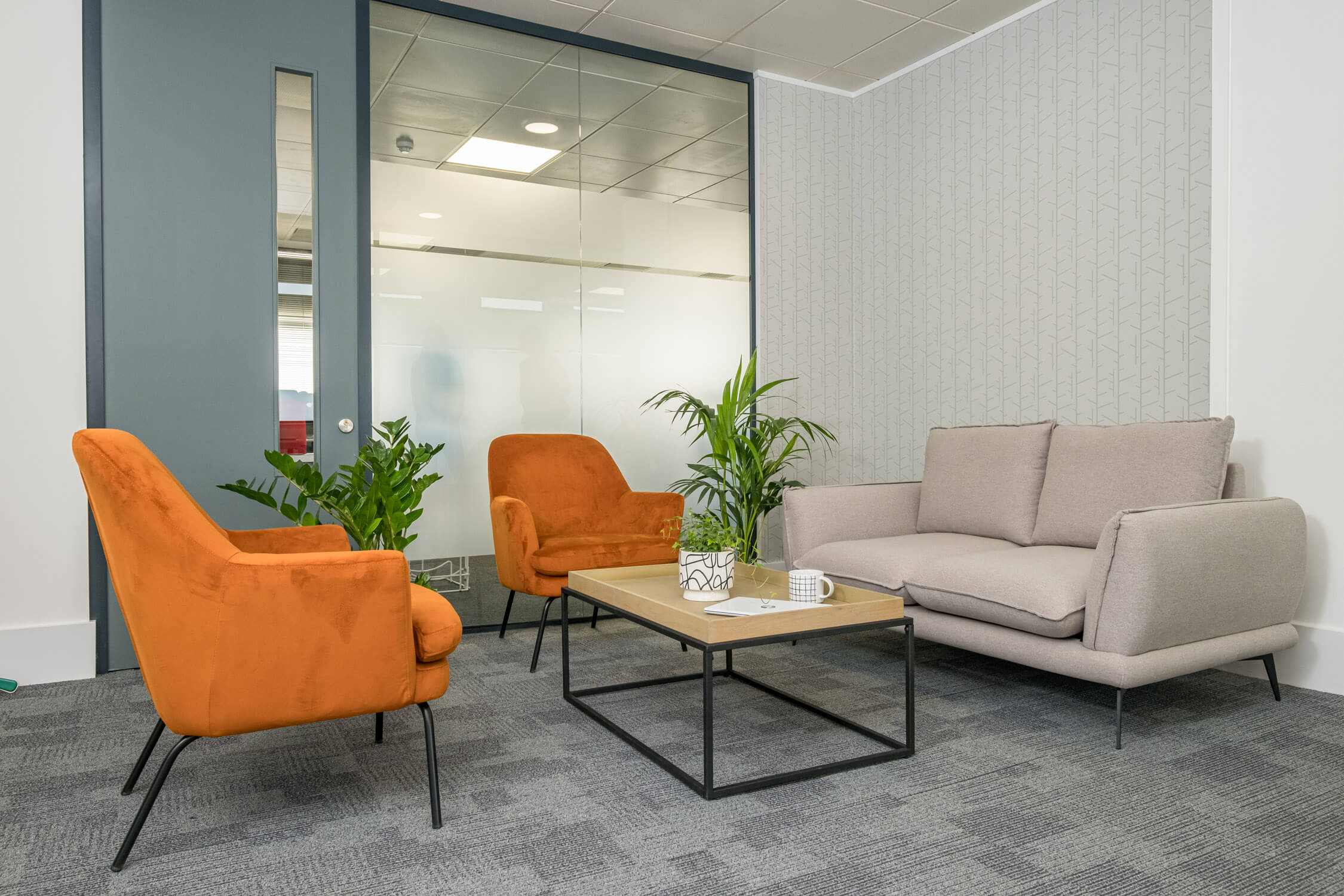 A lounge space in an office. Four sofas surround a coffee table.