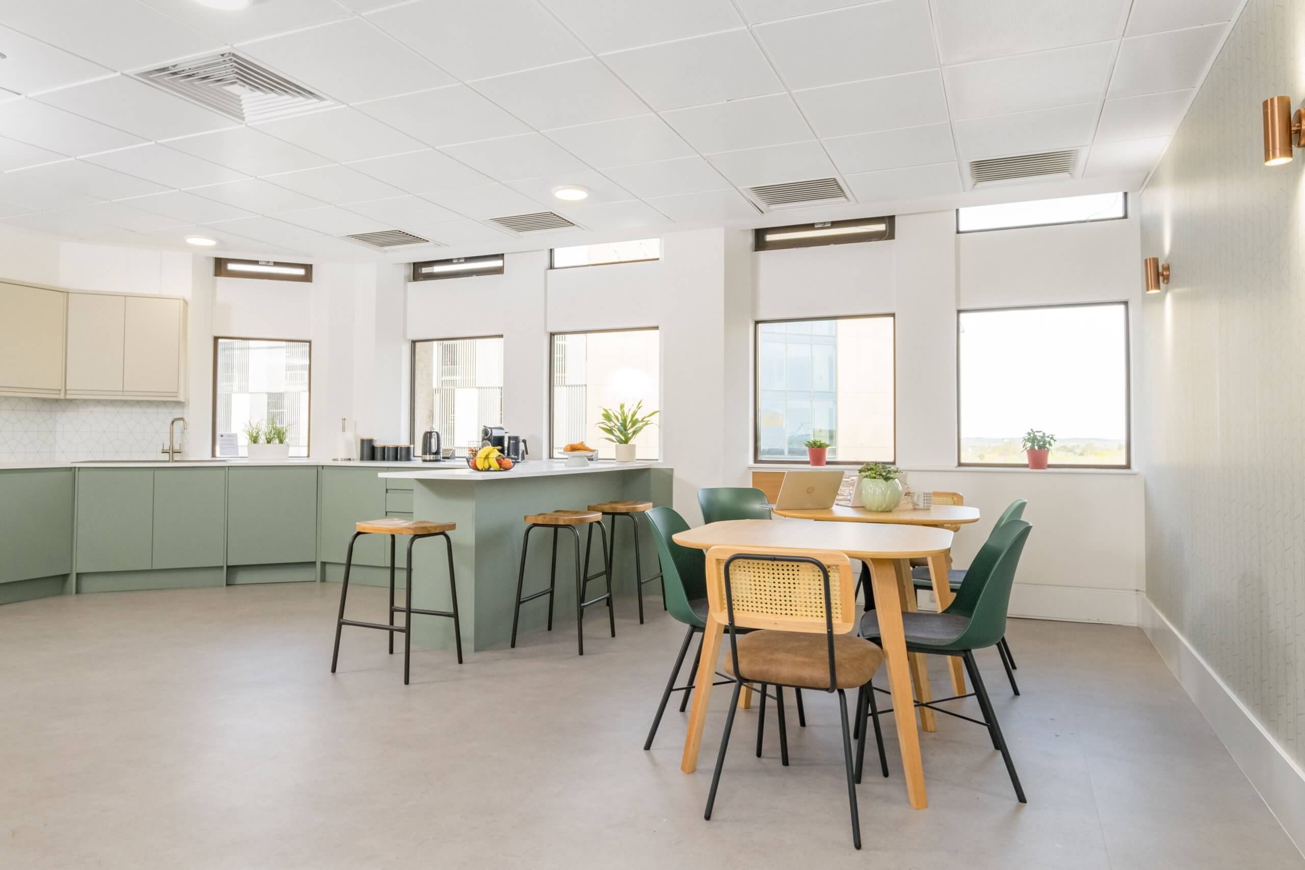 An office kitchen with tables, chairs and a kitchen island.