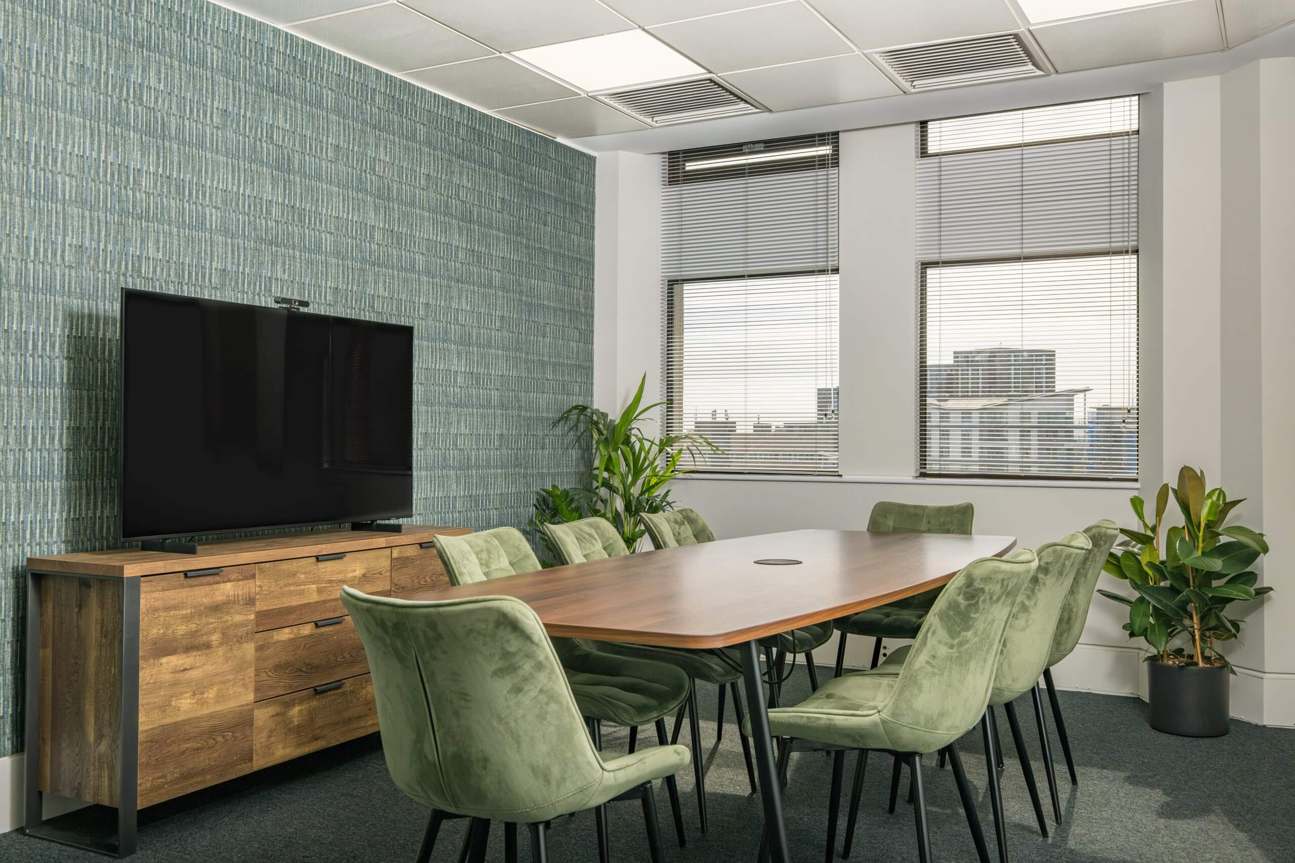 Meeting room with eight chairs, a large table and a screen for presenting.